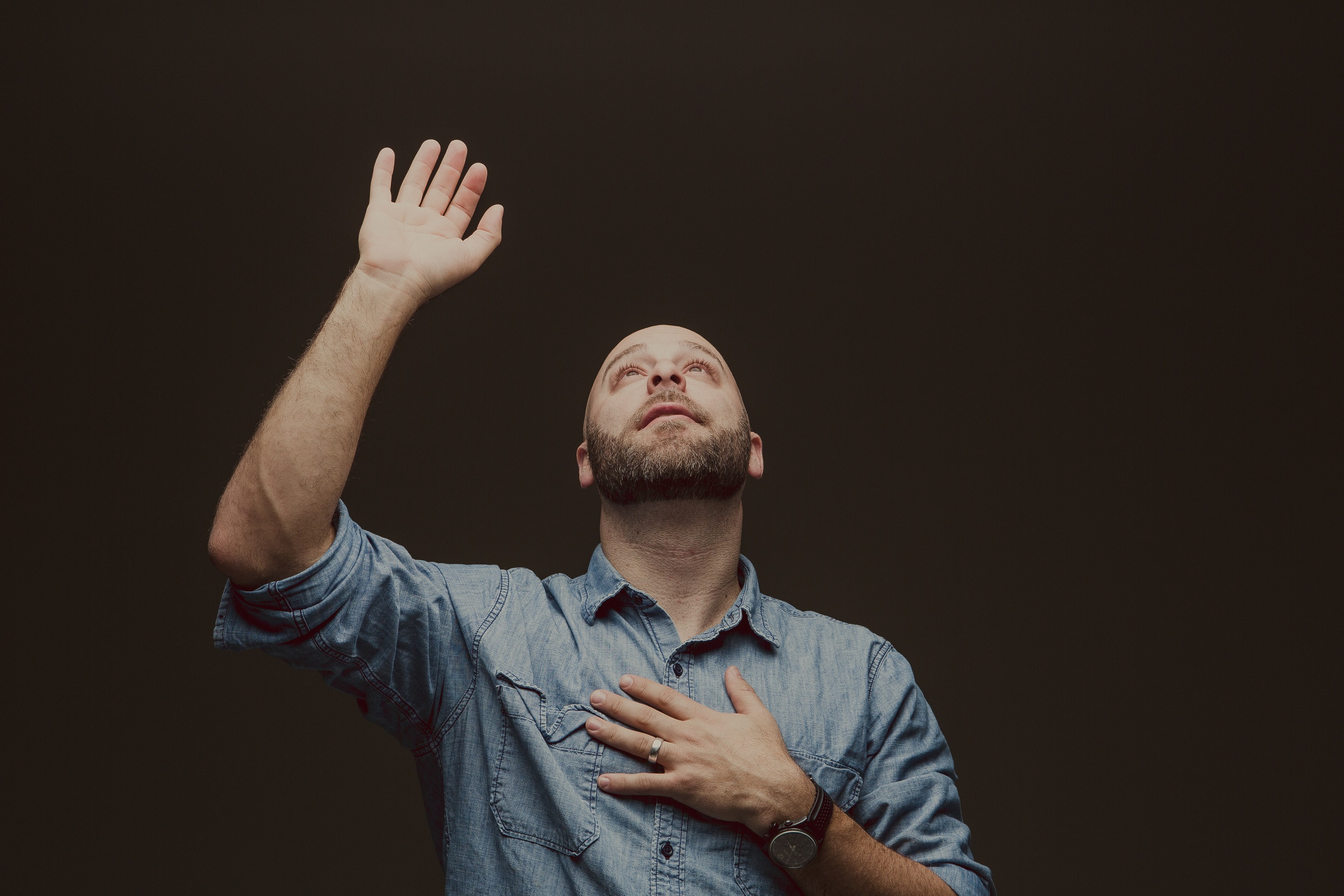 man worshipping with hand up, looking up