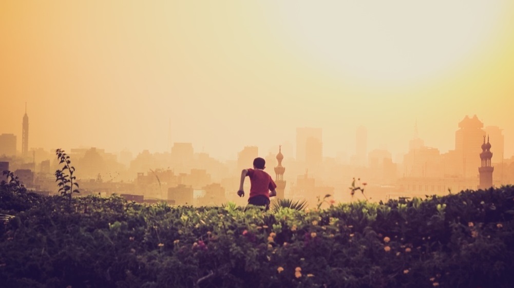 man running up hill into city