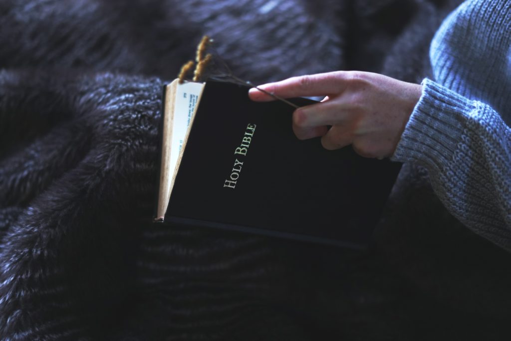 woman opening pages of Bible on her lap